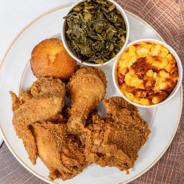 A Chick N' Friends fried chicken meal with collard greens, mac and cheese, and cornbread.