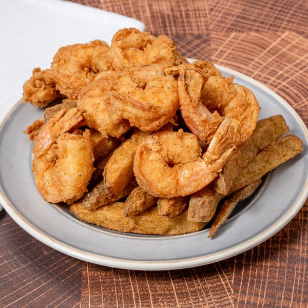 A plate of golden-brown fried shrimp and potato wedges from Chick N' Friends.