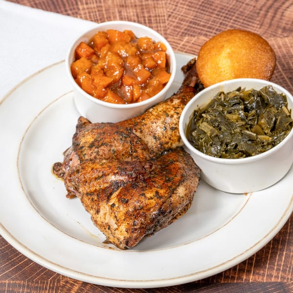 Chick N' Friends fried chicken with sides of candied yams, collard greens, and a cornbread muffin.